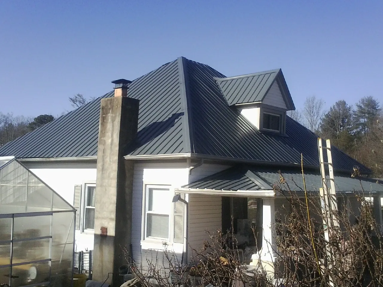 Dark blue standing seam metal roof on a white farmhouse with dormer — Slate & Tile Roof Repair by Roofing Brothers in Cedar Glen