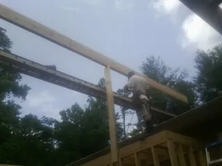 Carpenter setting a ridge beam over a new addition frame — Ice Dam Removal by Roofing Brothers in Cedar Glen