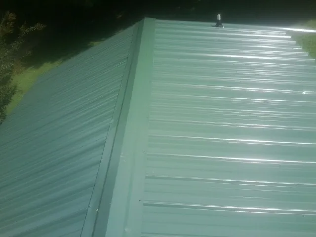 New green metal panels meeting at the ridge of a roof — Flat Roof Repair work by our crew in Cedar Glen