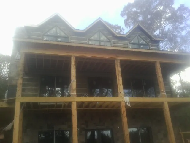 Dormers and porch framing on a large log home under construction — Roof Coating work by our crew in Cedar Glen