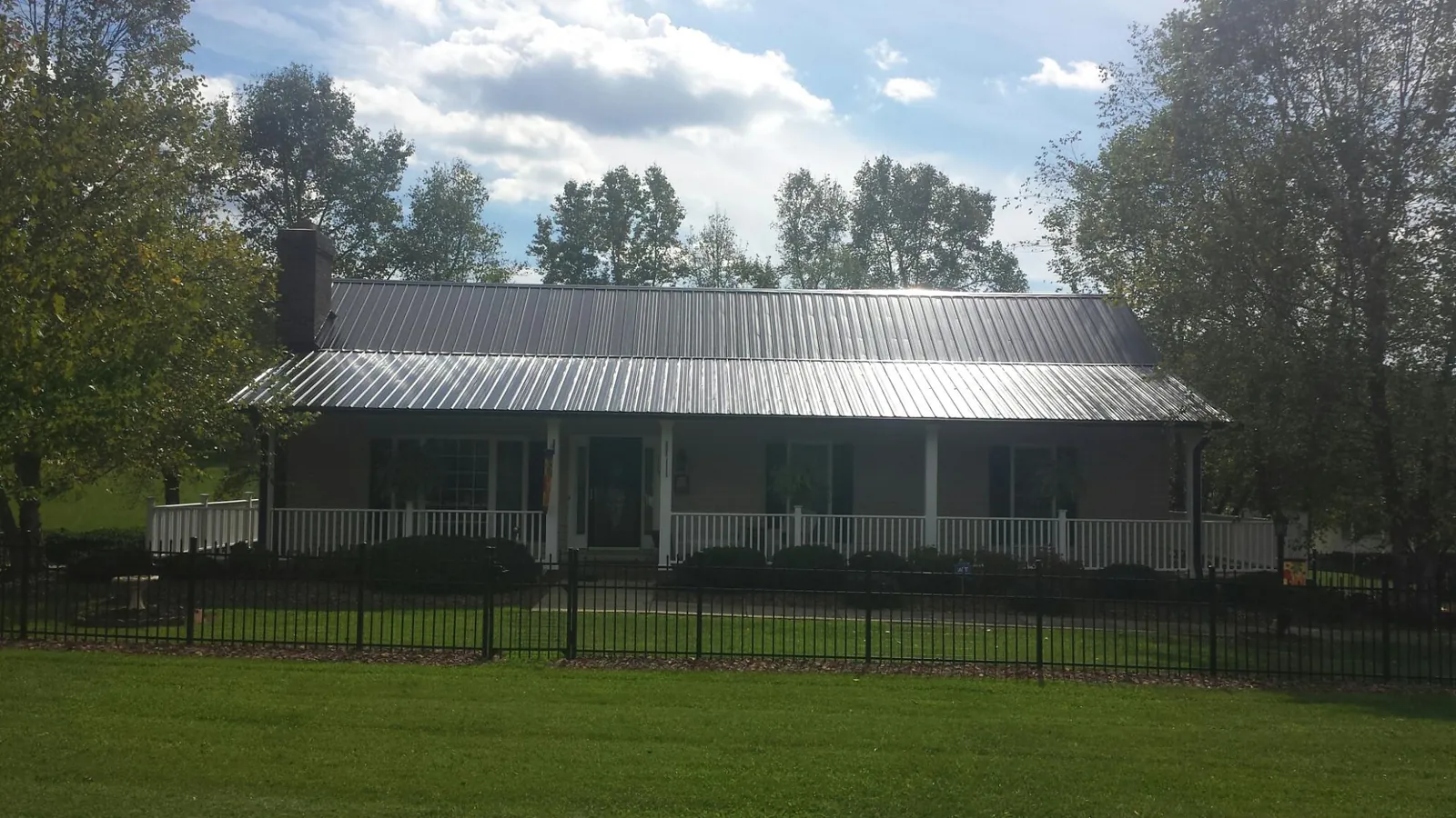 Gray metal roof on a brick ranch with a full width front porch — Gutter Guard Installation work by our crew in Cedar Glen