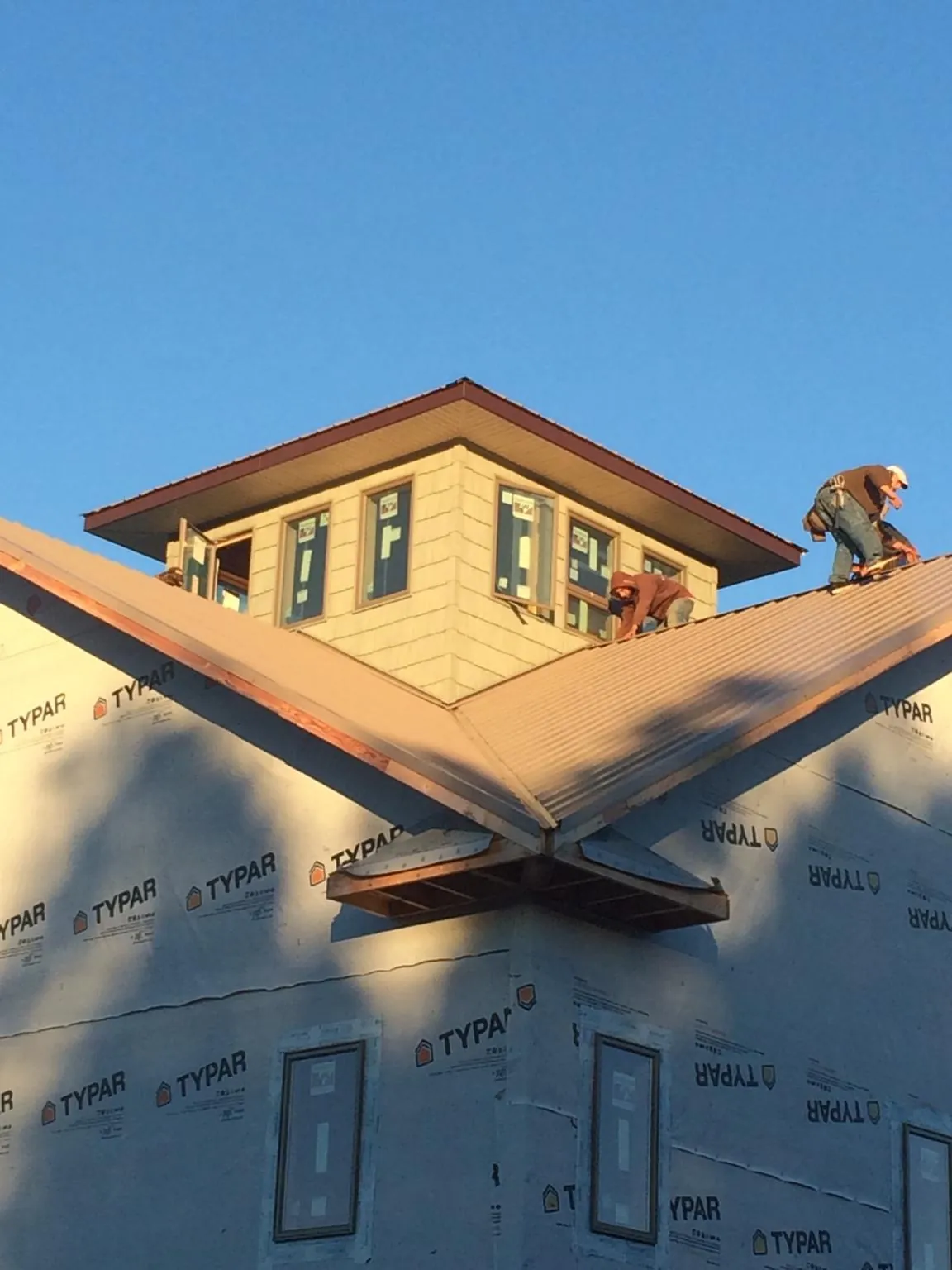 Roofers working around a rooftop cupola on a new metal roof at sunset — Roof Waterproofing in Cedar Glen by Roofing Brothers